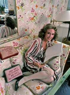 a woman sitting on top of a couch holding a piece of paper in her hand