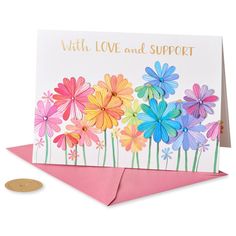 a card with colorful flowers on it and a gold coin sitting next to the card