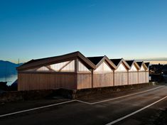 a row of wooden buildings sitting on the side of a road next to a body of water