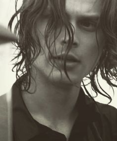 black and white photograph of a young man with long wavy hair looking at the camera