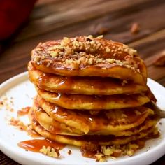 a stack of pancakes covered in caramel sauce on a white plate with pecans