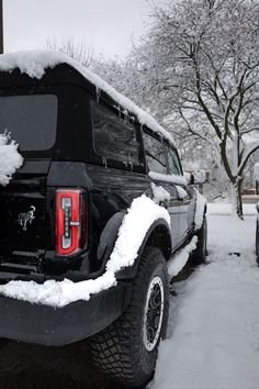 a black truck covered in snow next to trees