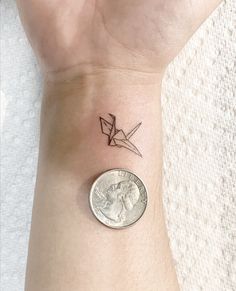 a small wrist tattoo with an origami bird on the left side of it