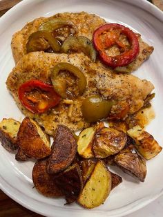 a white plate topped with chicken, potatoes and peppers