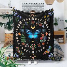 a black wall hanging with a blue butterfly on it's side, surrounded by potted plants