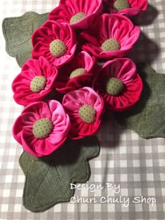 pink flowers with green leaves on a checkered cloth tableclothed surface, ready to be made into an applique