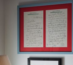 two framed letters are on the wall next to a lamp with a red and blue frame