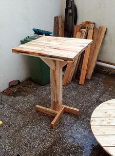 a wooden table sitting in the middle of a room next to a pile of wood