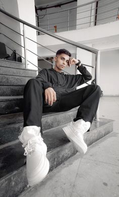 a man sitting on some stairs wearing white sneakers