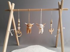 several wooden toys hanging from hooks on a white carpeted floor in front of a gray wall