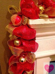 a red and gold christmas wreath sitting on top of a fireplace