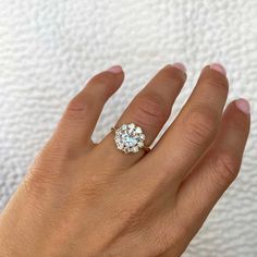 a woman's hand with a diamond ring on top of her finger, and the other hand holding an engagement ring