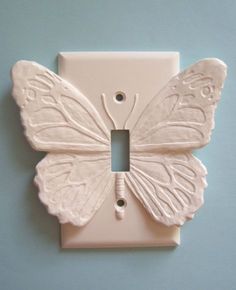 a white butterfly light switch plate on a blue wall