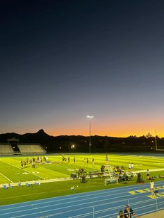 the sun is setting on an empty football field