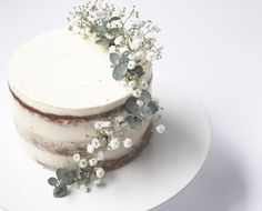 a cake with white frosting and flowers on the top is sitting on a plate