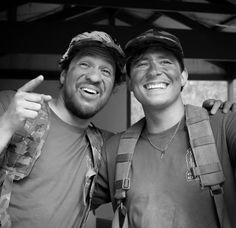 two men standing next to each other in front of a building