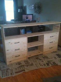 an entertainment center made out of wood with newspaper on the floor in front of it