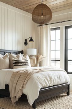 a bedroom with a bed, lamps and windows in the room that has white paneling on the walls