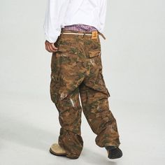 The Ink-Splashed Camo Cargo Pants in green offer a perfect fusion of vintage style and modern craftsmanship. Featuring a bold camo pattern with striking white ink-splatter detailing, these pants bring a unique twist to the classic cargo look. The distressed, ripped accents add a rugged edge, while the multi-pocket design ensures functionality. With adjustable waistband buckles and a leather logo patch on the back, these pants are crafted from premium 100% cotton and offer a slightly oversized fi Military Style Pants For Streetwear, Military Style Full Length Parachute Pants For Streetwear, Baggy Military Bottoms For Streetwear, Camouflage Streetwear Bottoms Full Length, Camouflage Full-length Bottoms For Streetwear, Camouflage Full Length Bottoms For Streetwear, Camouflage Wide Leg Pants For Streetwear, Full Length Camouflage Bottoms For Streetwear, Wide Leg Camouflage Pants For Streetwear