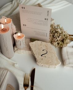 the table is set with candles, napkins and place cards for guests to use