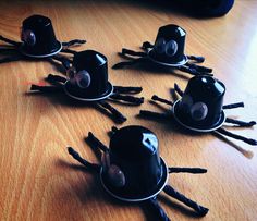 four black cups with eyes and sticks sticking out of them sitting on a wooden table