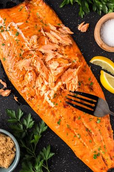 a large piece of salmon on top of a table with lemons and parsley