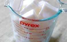 a measuring cup filled with sugar cubes on top of a table