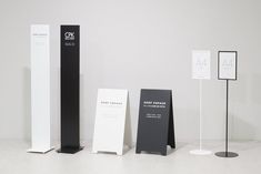 three tall black and white stands next to each other on the floor in front of a wall