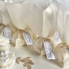 two white flowers are sitting next to each other on a table with ribbons and tags