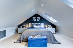 an attic bedroom with white walls and blue accents on the bed, along with two nightstands