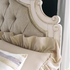 a close up of a bed with pillows and a blanket on top of it's headboard