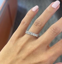 a woman's hand with a wedding ring on her finger and pink manicures