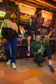 three people are posing for a photo in front of an arcade machine with neon lights