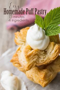 homemade puff pastry with whipped cream and mint leaves on top, sitting on a piece of parchment paper