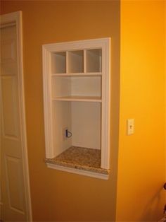 an empty shelf in the corner of a room that is painted yellow and has white trim