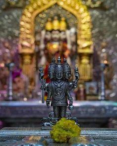 a small statue sitting on top of a table in front of a alter with flowers