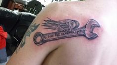 a tattoo on the back of a man's shoulder that has a wrench with wings