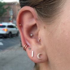 a close up of a person with ear piercings and a car in the background