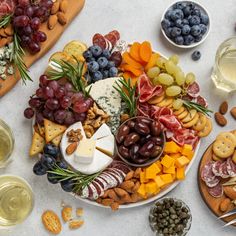 an assortment of cheeses, crackers and grapes on a platter