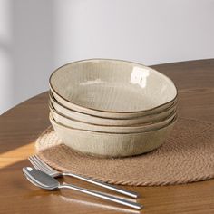 a stack of white plates sitting on top of a wooden table next to silverware