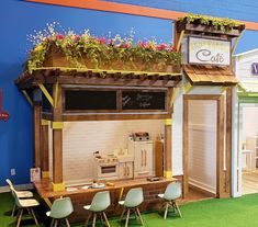 a small booth with chairs and tables in front of it that has a cafe sign on the roof