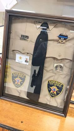 a display case with an officer's uniform and tie in it on top of a wooden table