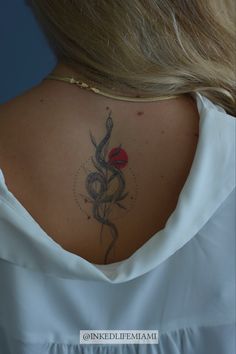 the back of a woman's neck with a rose tattoo on her left side