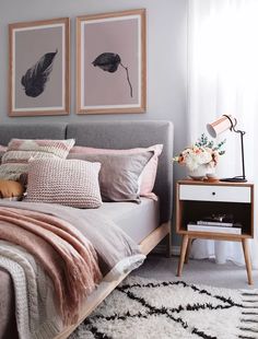 a bedroom with pink and grey bedding, two pictures on the wall above the bed