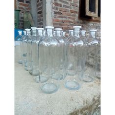 several empty glass bottles lined up on a ledge in front of an old brick building