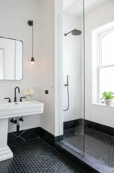 a bathroom with black and white tile flooring, two sinks and a shower stall