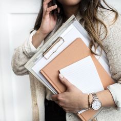 a woman holding a binder and talking on the phone