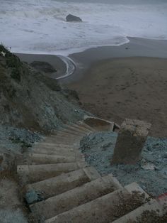 some stairs going up to the beach with waves coming in