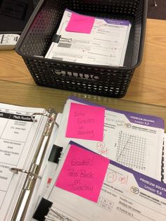 two binders with notes attached to them sitting on a desk next to a laptop