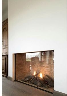 a fire place in the middle of a living room with wood floors and white walls